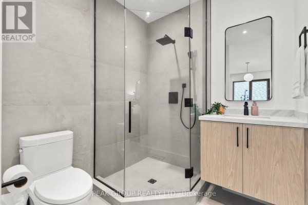 Modern bathroom with glass shower, rainfall showerhead, wood vanity, and black faucet - 111 Millpond Road Niagara On The Lake