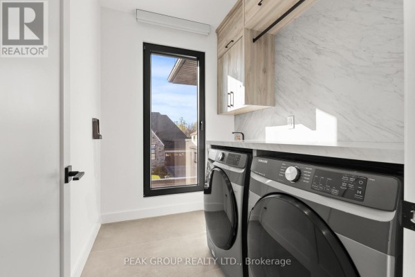 Modern open-concept living, dining, and kitchen with island seating and designer lights - 111 Millpond Road Niagara On The Lake