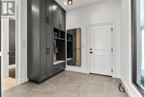 Modern kitchen island with seating, dark cabinetry, and marble backsplash - 111 Millpond Road Niagara On The Lake
