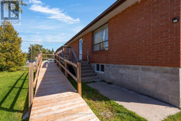 Close-up view of a brick house exterior with a wooden ramp, concrete foundation, and windows. - 111 Osborne Street, Tay