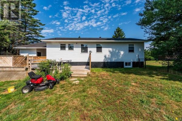 Rear exterior of the white house showing a wooden deck, lawn, and fence. - 111 Prince William Street, Digby