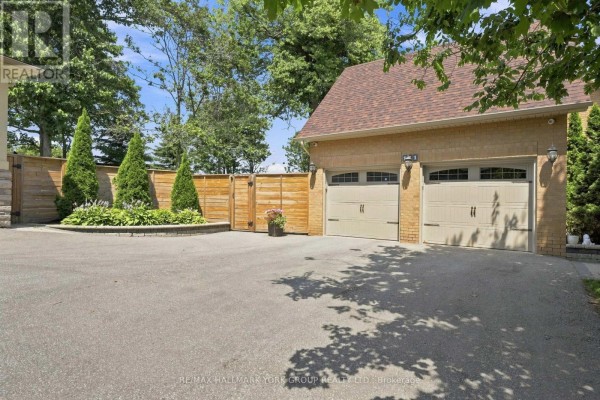 Detached two-car garage with light-colored doors, adjacent to a wooden privacy fence and asphalt driveway. - 111 Whispering Pine Trail, Aurora