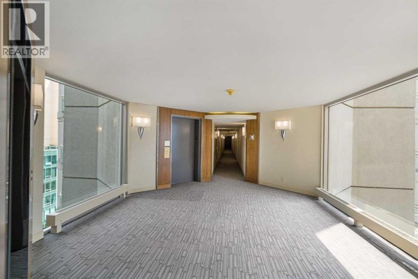 Hallway with patterned carpet, large windows, and elevator doors. - 1110, 804 3 Avenue Sw, Calgary
