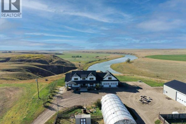 Aerial view of the farmhouse, detached garage, greenhouse, and surrounding rural landscape. - 111072 Rr#151, Purple Springs