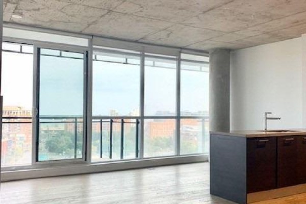 Open concept living area with large windows, balcony access, and a kitchen island with sink. - 1111 - 318 King Street E, Toronto