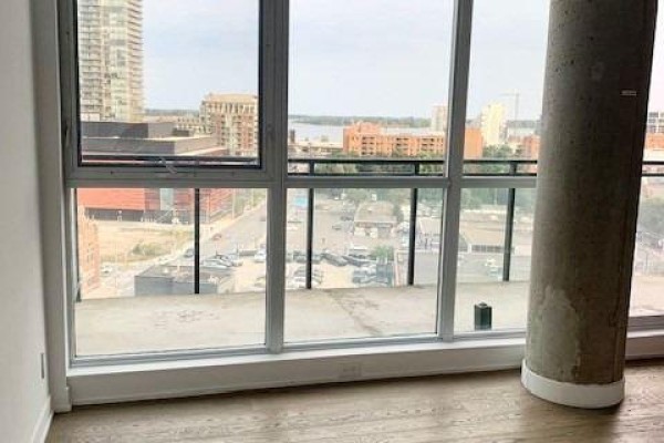 Living area with floor-to-ceiling windows offering a city view, and a large concrete column. - 1111 - 318 King Street E, Toronto
