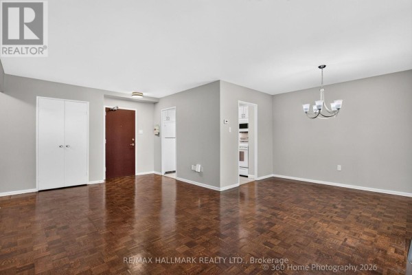 Living room with dark hardwood floors, grey walls, white bi-fold doors, and a ceiling light fixture. - 1111 - 360 Ridelle Avenue, Toronto