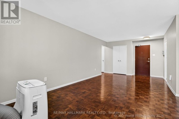 Living room showing dark hardwood floors, grey walls, and a portable air conditioning unit. - 1111 - 360 Ridelle Avenue, Toronto