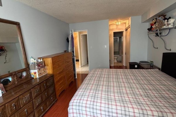 Bedroom with a dresser, mirror, bed, and an open doorway leading to a bathroom. - 1111 - 633 Bay Street, Toronto