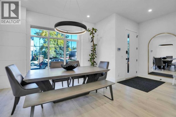 Dining area with concrete table, grey chairs, bench, and view through large windows to street. - 1111 43 Street Sw, Calgary