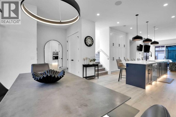 Open-concept living area with dining table, entrance, stairs, and modern kitchen with island. - 1111 43 Street Sw, Calgary