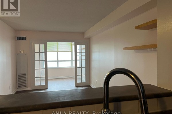 View from the kitchen counter looking into the living room and sunroom through French doors. - 1112 - 1883 Mcnicoll Avenue, Toronto