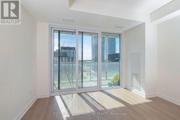 Empty living room with light wood-look flooring and view of Toronto skyline from balcony. - 1112 - 425 Front Street E, Toronto