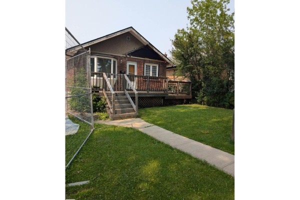Front view of a brick house with a deck, steps, and a fence. - 11124 97 St Nw Nw, Edmonton