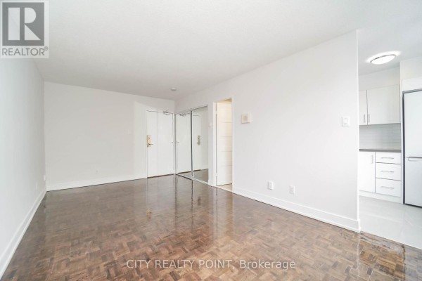Empty living space with hardwood floors and a partial view of the kitchen area. - 1113 - 33 Isabella Street, Toronto