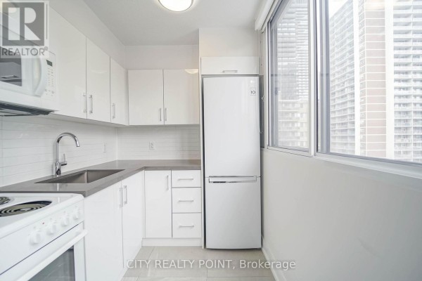 White galley kitchen with stainless steel appliances, gray countertops, and a large window. - 1113 - 33 Isabella Street, Toronto