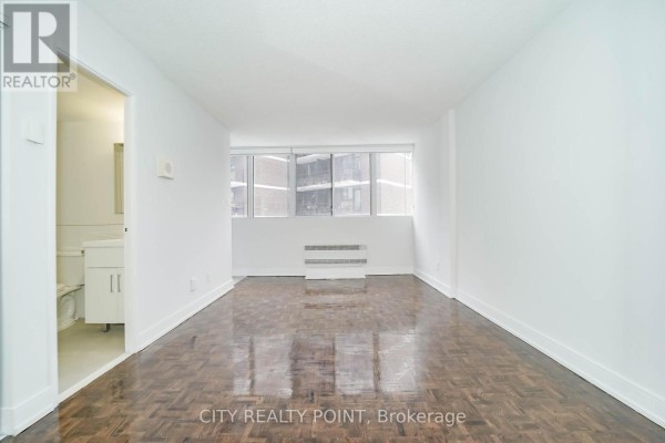 View of the main room from the entrance, showing the hardwood floor and a window with blinds. - 1113 - 33 Isabella Street, Toronto