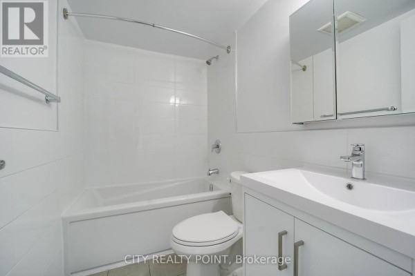 Small bathroom with a white tub, toilet, and vanity with a medicine cabinet. - 1113 - 33 Isabella Street, Toronto