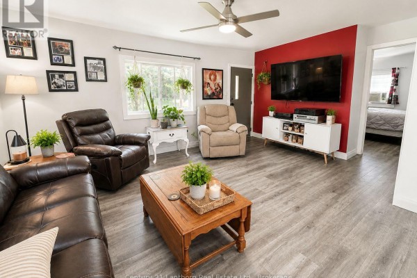 Living room with a brown leather couch, a tan recliner, and a large TV on a white media console. - 1113 Clark Road, Frontenac