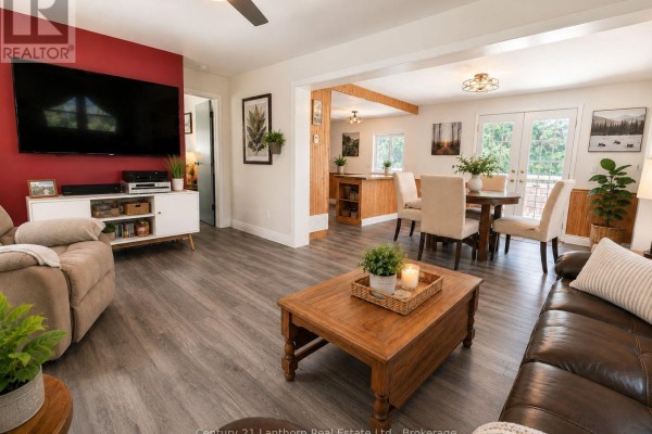 Living room with a view of the dining area and kitchen, featuring wood paneling. - 1113 Clark Road, Frontenac