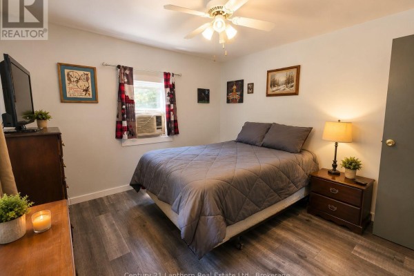 Bedroom with a queen-size bed, dark wood furniture, and a window with checkered curtains. - 1113 Clark Road, Frontenac
