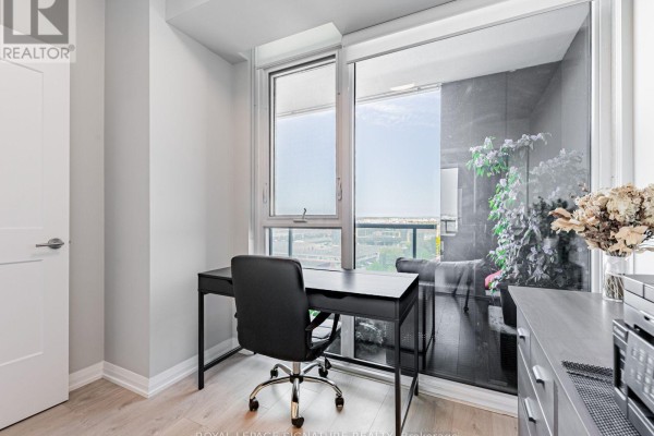 View of a home office desk, grey dresser, and sliding glass doors leading to a balcony. - 1114 - 7895 Jane Street, Vaughan