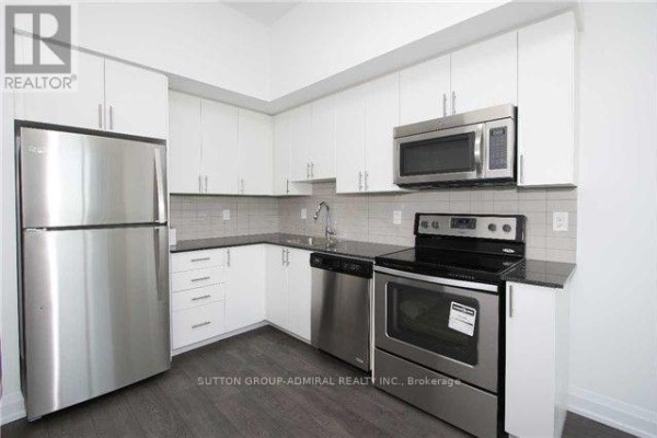 Galley-style kitchen with white cabinetry, stainless steel appliances, and dark countertops. - 1114 - 7900 Bathurst Street, Vaughan