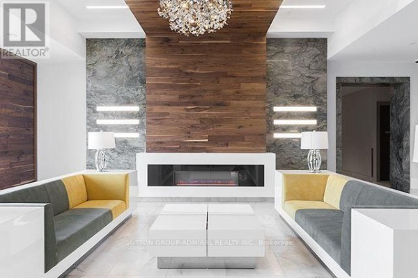Building lobby with a modern fireplace, decorative wall panels, and contemporary seating. - 1114 - 7900 Bathurst Street, Vaughan
