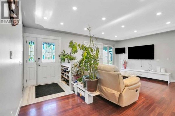 Interior view of a living room with a beige recliner, plants, and a white front door. - 1115 Marcombe Crescent Ne, Calgary