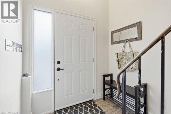 Interior foyer with a white door, a bench, mirror, and staircase railing. - 1115 Paramount Drive Unit# 50, Stoney Creek