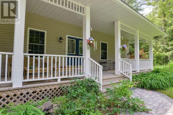 Close-up of the front porch with white railings, wooden floorboards, and a blue front door. - 1115 Partridge Lane, Bracebridge)