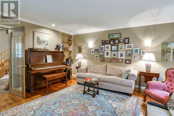 Living room with a grand piano, beige sofa, patterned rug, and a gallery wall of framed photos. - 1115 Partridge Lane, Bracebridge)