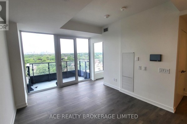 View of the living space with a balcony overlooking trees and city skyline. - 1116 - 28 Ann Street, Mississauga