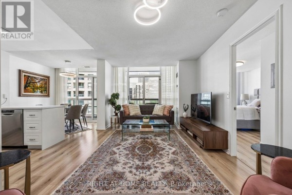 Living room with gray sofa, glass coffee table, wooden media console, and view of city. - 1116 - 503 Beecroft Road, Toronto