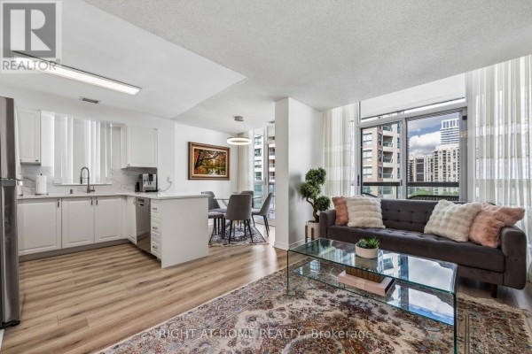 Open concept living and kitchen area with white cabinets and dining table. - 1116 - 503 Beecroft Road, Toronto