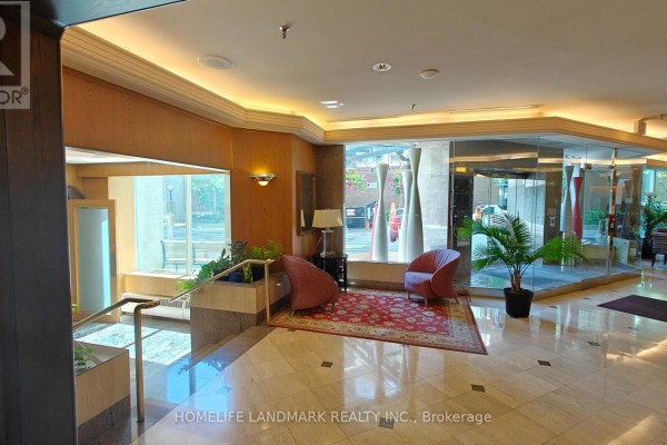 Apartment building lobby with marble floors, two chairs, and potted plants. - 1116 - 942 Yonge Street, Toronto