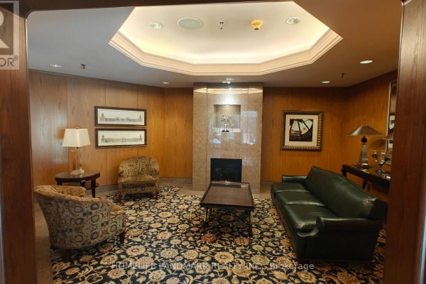 Apartment building lounge area with fireplace, sofa, chairs, and patterned carpet. - 1116 - 942 Yonge Street, Toronto