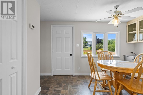 Dining area with a round wooden table and four chairs, facing a window and a doorway. - 1116 St. Charles Road, Souris West