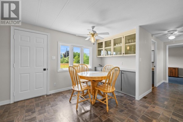 Dining area with a round wooden table and four chairs, featuring built-in cabinets and a window. - 1116 St. Charles Road, Souris West