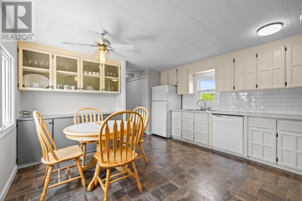 Open concept kitchen and dining area with white cabinets, countertops, and a round wooden table. - 1116 St. Charles Road, Souris West