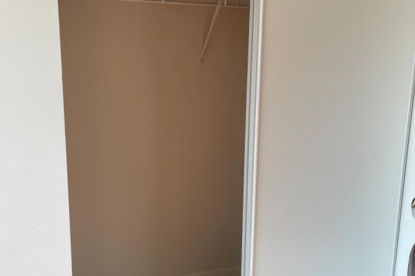 Empty walk-in closet with a single shelf and beige walls. - 1117 - 17 Anndale Drive, Toronto