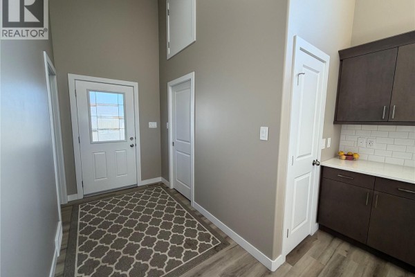 Another view of the hallway and entrance, showing the proximity to the kitchen cabinetry. - 1119 Birchwood Avenue, Good Spirit Lake