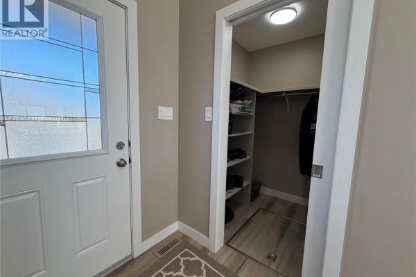 Entrance hallway with a glass-paned door and an adjacent walk-in closet with shelving. - 1119 Birchwood Avenue, Good Spirit Lake