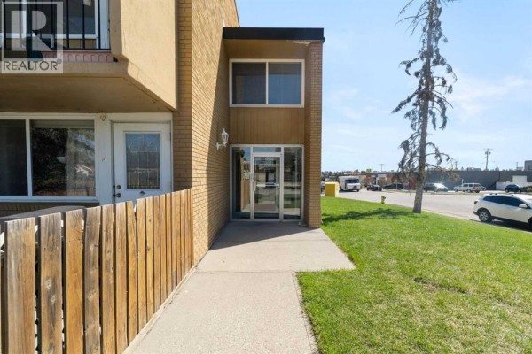 Entrance to the apartment building with glass doors and windows, a concrete walkway. - 112, 7007 4a Street Sw, Calgary