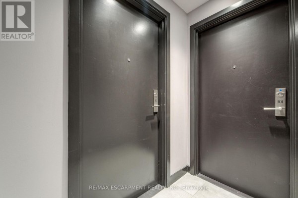 Hallway with two dark grey apartment doors, one labeled "101". - 112 - 2433 Dufferin Street, Toronto