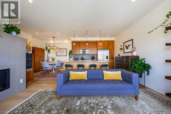 Living room and kitchen area with blue sofas, fireplace, and island. - 112 21 Street Nw, Calgary