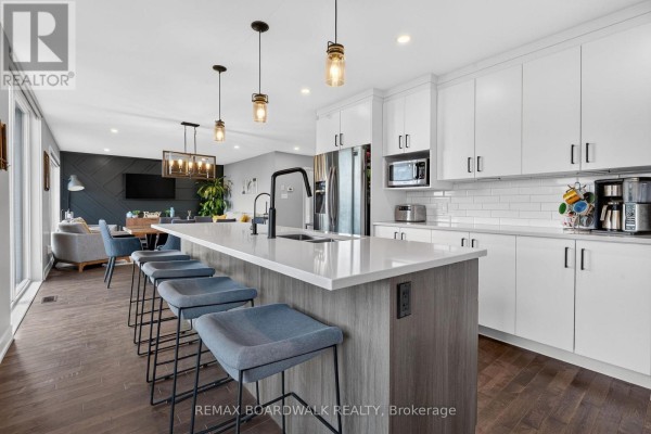Modern kitchen island with bar stools, subway tile backsplash, and pendant lights - 112 Argile Street Casselman