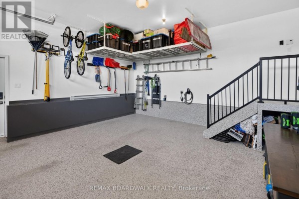 Organized garage with overhead storage, bikes, tools, and epoxy floor - 112 Argile Street Casselman