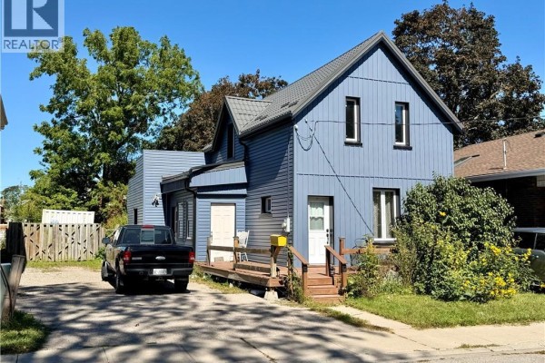 Side view of a two-story blue house with a metal roof and attached garage. - 112 Arthur Street, Brantford