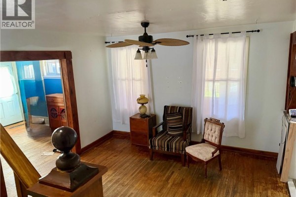 Living room with light blue walls, wooden floors, and two chairs near windows. - 112 Arthur Street, Brantford